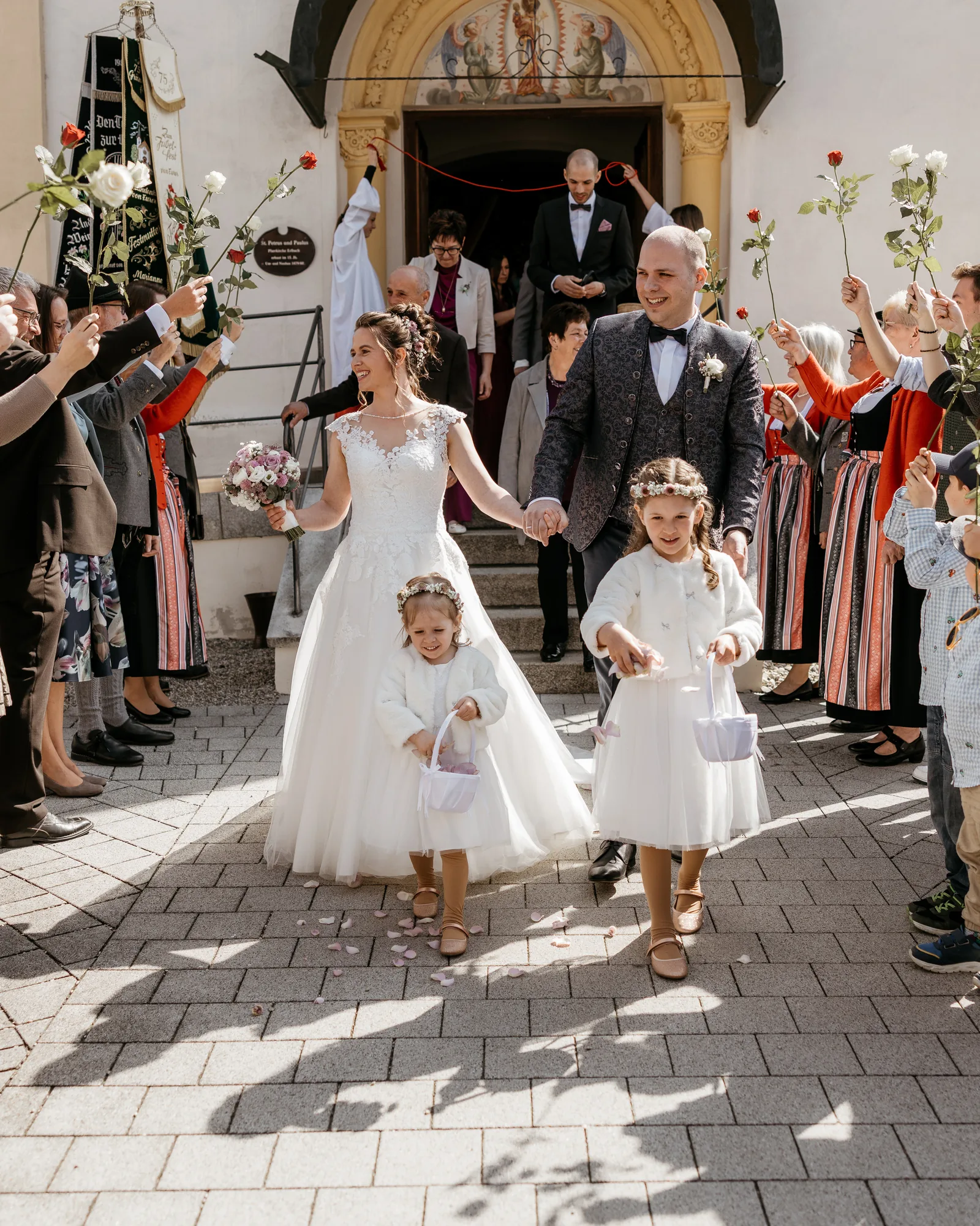 Brautpaar beim Auszug aus der Kirche mit Blumenkindern – Hochzeitsreportage in Bayern