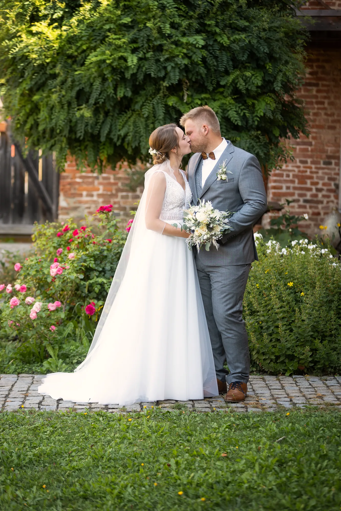 Kuss des Brautpaars vor einem Rosengarten – Hochzeitsfotograf aus Niederbayern