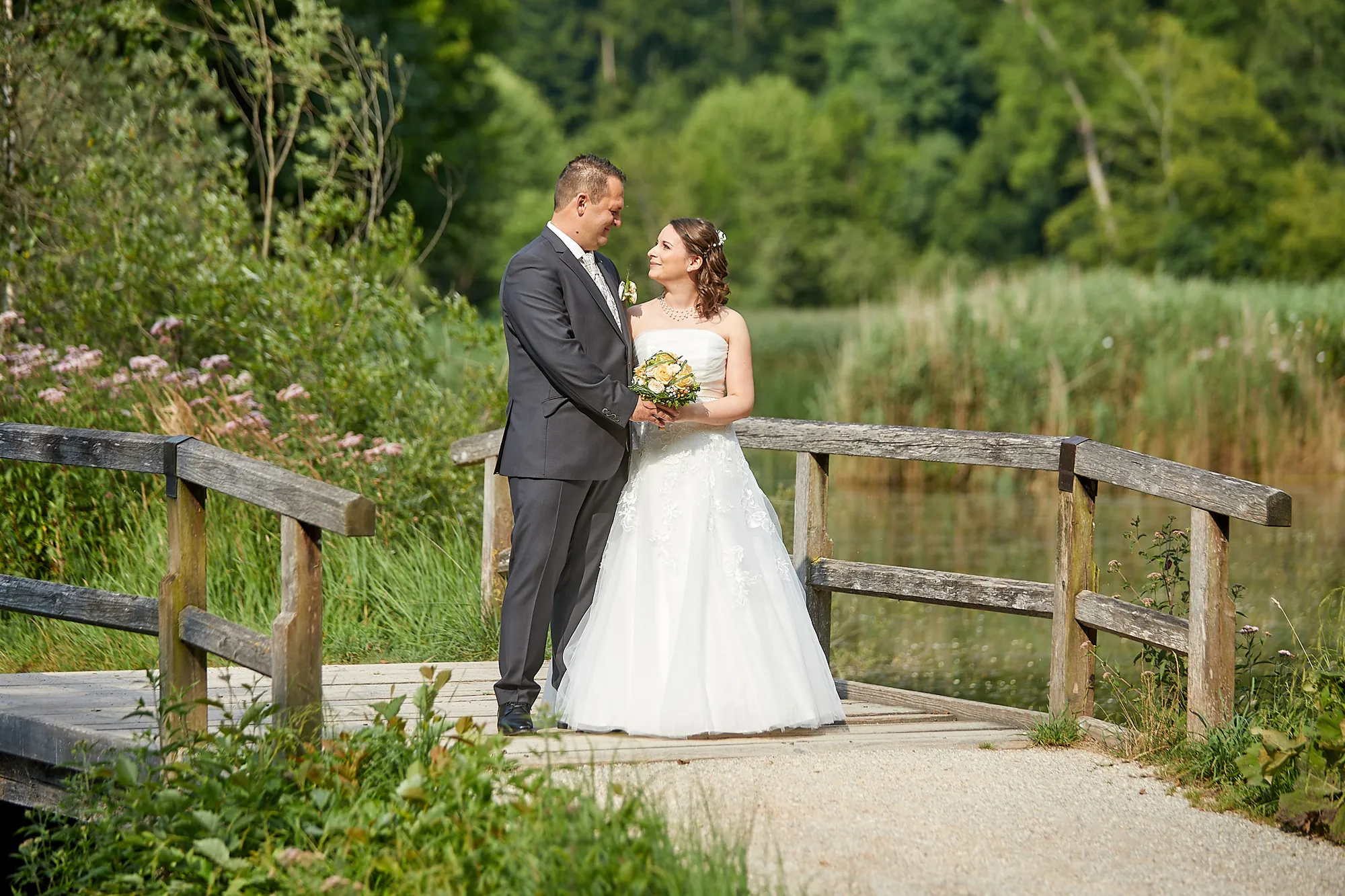 Brautpaar auf einem Holzsteg im Grünen – Hochzeitsfotograf aus Niederbayern